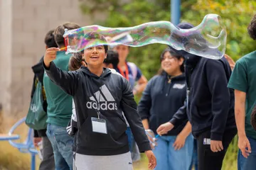 Student making large bubbles with a bubble wand
