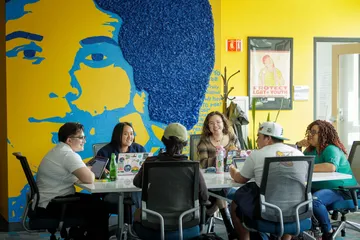 Diverse group of students at table with mural behind it