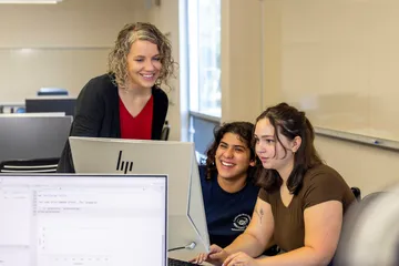 Three girls are looking into a Computer Screen