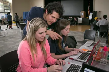 Two people on laptop with student helping them