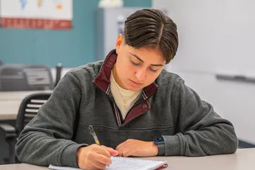 Student at a desk writing in a note book