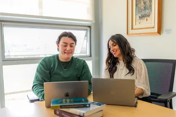 A masters of business administration student and professor sitting down together at a table collaborating