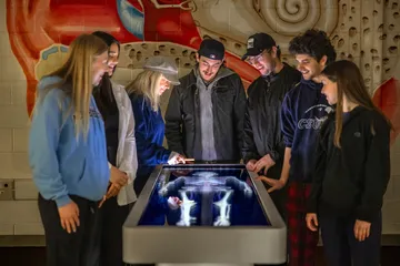A professor giving a presentation to a group of students using a digital anatomy board