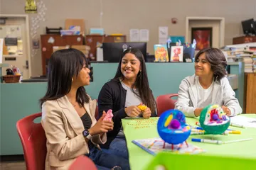 A social work credential student sitting at desk in a classroom teaching two kids