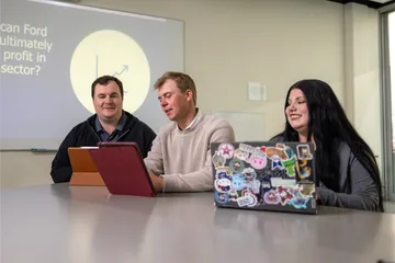 A group of three business administration students sitting down collaborating together