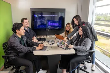 A group of four business administration students and a professor collaborating together