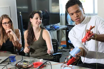 Three �鶹�� Students programming prosthetic arms