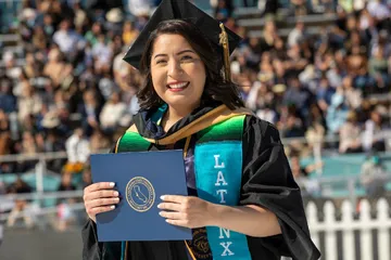 Latinx Grad holding diploma at the 2022 Commencement | Photo by Brent Dundore-Arias