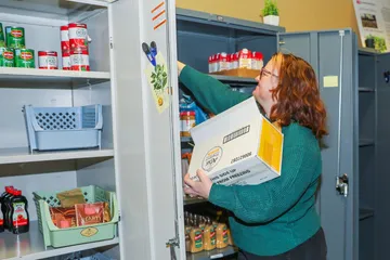 Basic Needs coordinator Robyn DoCanto stocks shelves in the pantry, which provides food-insecure students with important nutrition.