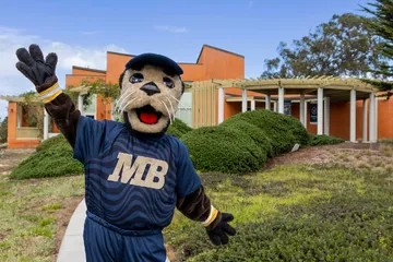 Monte Rey, CSUMB mascot, posing in front of the Alumni and Visitor Center Building