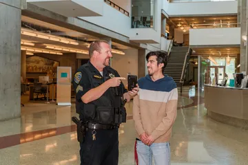 A UPD officer showcasing an OTTERalert to a student
