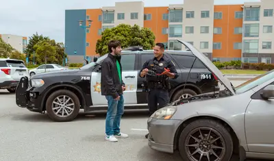 Another photo of a UPD officer assisting a student with a car jumpstart