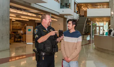 A UPD officer showcasing an OTTERalert to a student