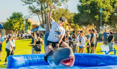 Student rides an electronic shark at RAFT Weekend