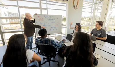 A group of students listening to their professor give a presentation