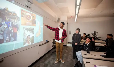 A student giving a presentation to the class on a self introduction slide