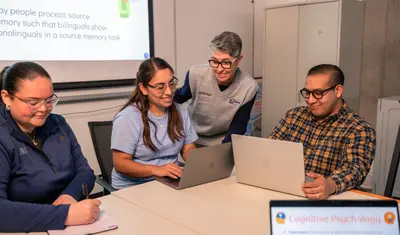 A group of people are smiling as they look at their laptops.