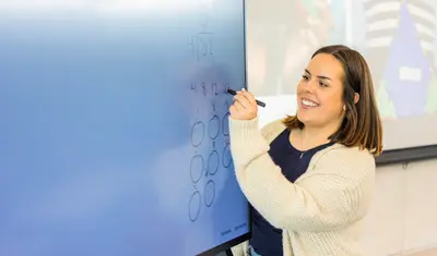 A student writing on the digital board