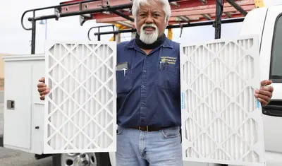 Augie Eclarin, from Facilities, holding a MERV 8 (left) and MERV 13 filters