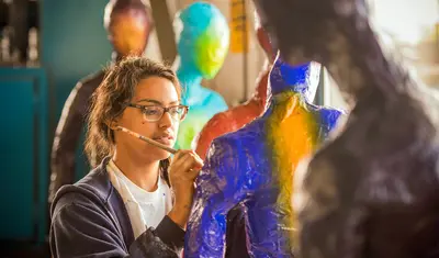 Student painting on a sculpture