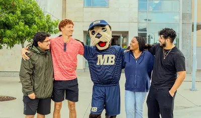 Monte hanging out with a group of students in front of the library
