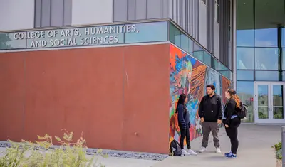 Students talking in front of the College of arts, humanities, and social sciences