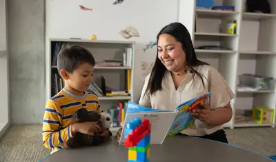 Student reading a story to a child in a classroom.
