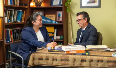 Two people having a discussion at a table and smiling at each other