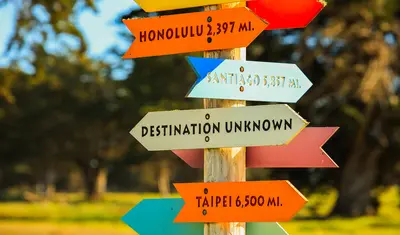 Colorful directional signs point to global destinations, symbolizing exploration and international connection.