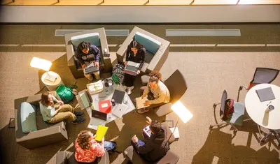 Students are sitting around the table in the library space