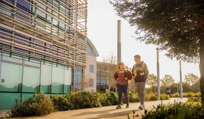 Two students walking along the BIT building and talking