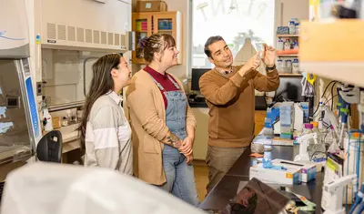 A faculty member guides students through a hands-on lab activity, demonstrating techniques in a collaborative learning environment