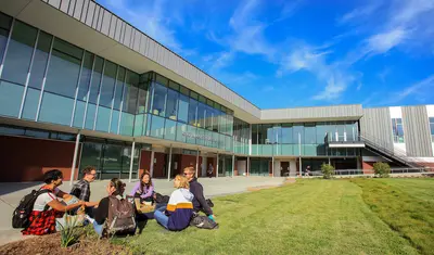 Group of students sitting on grass outside the CAHHS building