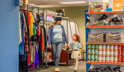 Adult and child walking through the clothing closet area of the Otter Care Hub.