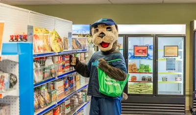 CSUMB mascot posing near pantry shelves inside the Otter Care Hub.