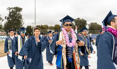 CSUMB graduates walking to their seats and posing for the picture