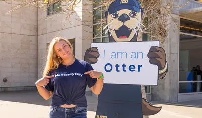 A student posing with a cutout of monte for admitted otter days