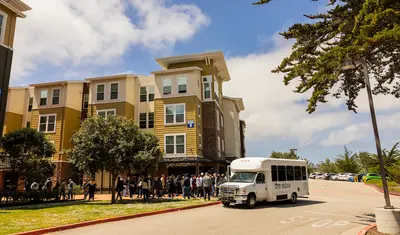 “The Wave” campus shuttle parked in front of university buildings.
