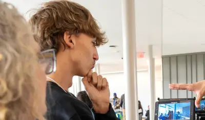 Student and family member talking to a faculty member inside a CSUMB building.