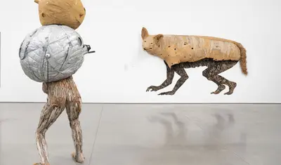 art installation man with bundle on back faces coyote