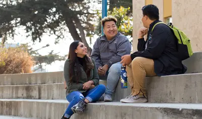 3 students sitting next to each other talking