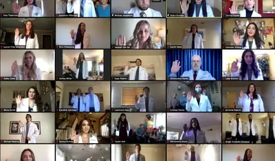 Physician assistant students raise their right hands while reciting an oath during the virtual White Coat Ceremony on Feb. 13.