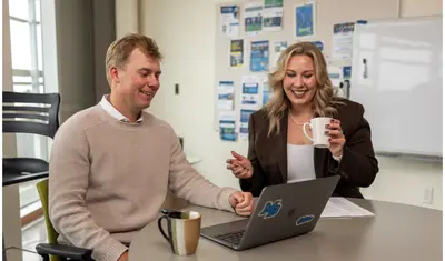 A business administration student and professor sitting down and collaborating together