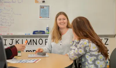 Teacher helping a kid read in the reading center