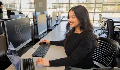 A student sitting down inside a computer lab in the business and information technology building