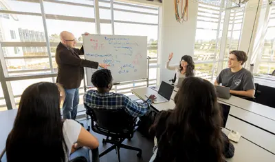A group of students listening to their professor give a presentation