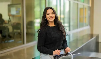 A student sitting with their laptop in the business and information technology building