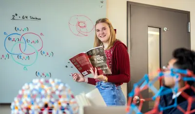 A statistics student writing on a whiteboard