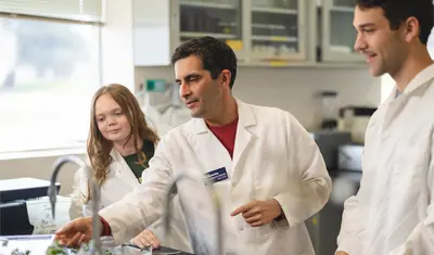 Professor showing two students something in a lab.
