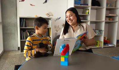 Student reading a story to a child in a classroom.